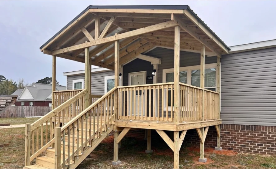 Covered porch with an open timber gable, wood railings and a wide staircase